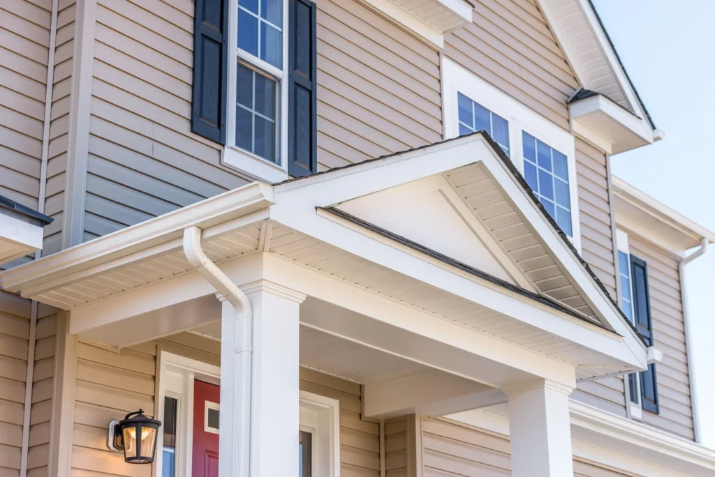 Portico leading to the entrance of vinyl horizontal lap siding covered building, with a roof structure over a walkway, supported by white rectangular columns on a single family home in suburband Maryland