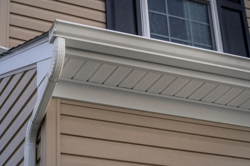 Gable with vinyl siding, white frame gutter guard system, fascia, drip edge, soffit, on a pitched roof attic at an American single family home in suburban MD.