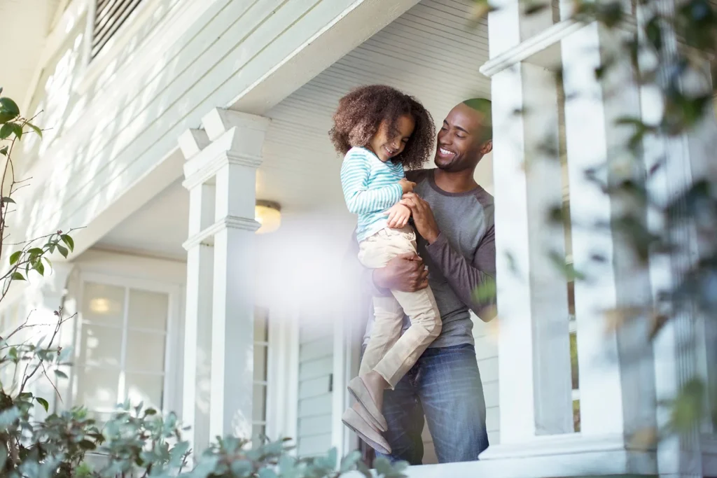 Smiling Father Holding Daughter Covered White Porch